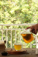 cup of tea, tea being poured into a transparent and white tea cup, teapot and tea cup with floral motif, darmkmood tea photo display