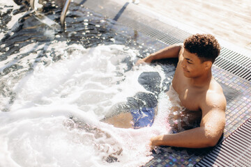 Young man relaxing in hot tub enjoying spa day