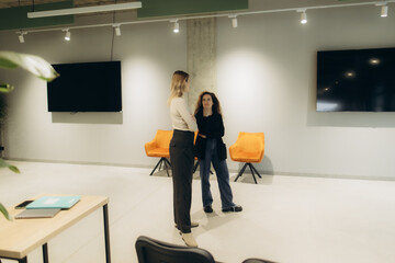 Two Women Engaging in Conversation in a Modern Office Space