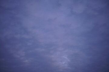 Violett und blau bedeckter Himmel am Abend mit etwas Sonne, die hindurch scheinen kann
