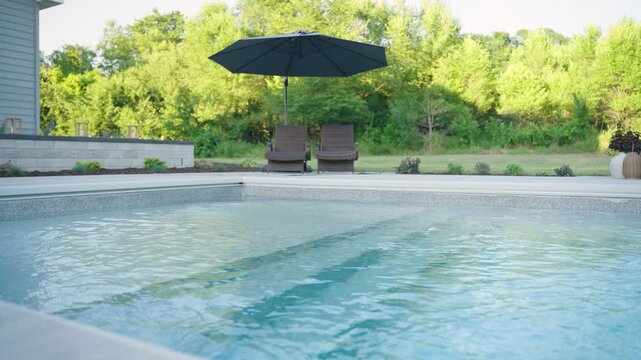 Close-up of submerged fiberglass pool steps with lounge chairs and umbrella.