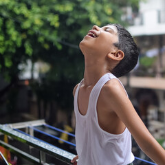 Little kid playing in summer rain in house balcony, Indian smart boy playing with rain drops during...