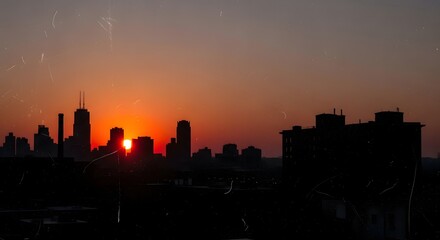 Dramatic sunset over a modern cityscape with the sun setting behind towering skyscrapers in a metropolitan downtown core.