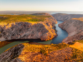 View of the Zrmanja River Canyon in Croatia, with winding turquoise waters cutting through limestone cliffs. A scenic natural wonder popular for kayaking and hiking