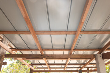 Roof structure under construction with metal sheet. Including sloped purlins, rafters, stud beams and columns. Concepts of architectural framing, structural engineering and roofing system.