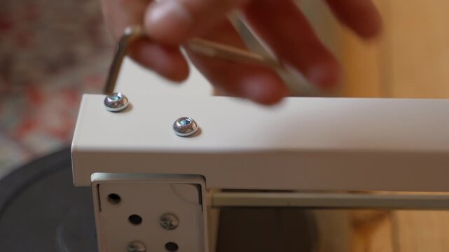 Assembling white furniture, close-up. Tightening parts with a hexagon
