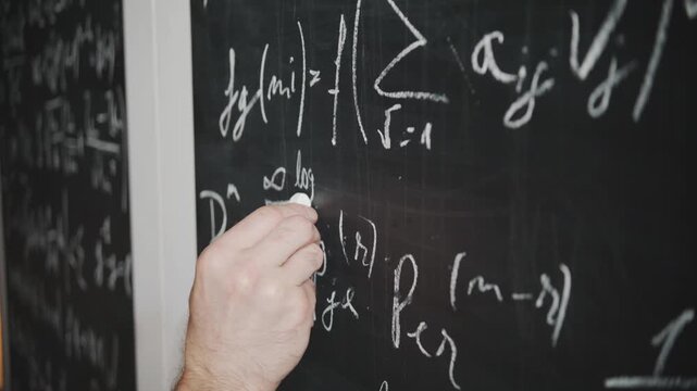 A close-up shot of a scientist's or teacher's hand writing a complex math or physics equation on a blackboard. Concept of education, academia, research, and problem-solving - Powered by Adobe