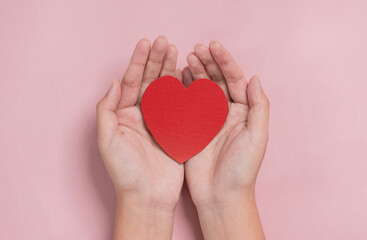 Obraz premium woman hands giving a red heart, red heart in young girl hands , health care, organ donation, family life insurance, world heart day, brain stroke. love concept.