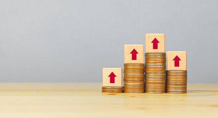 rising stacked coins with arrow up on wooden cubes, copy space