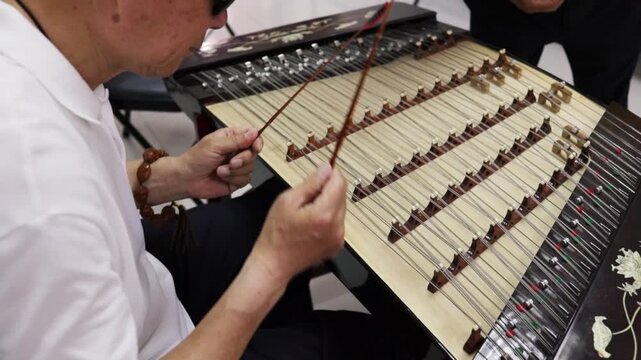 Chinese musician plays Dulcimer - old wooden musical instrument. Close up.