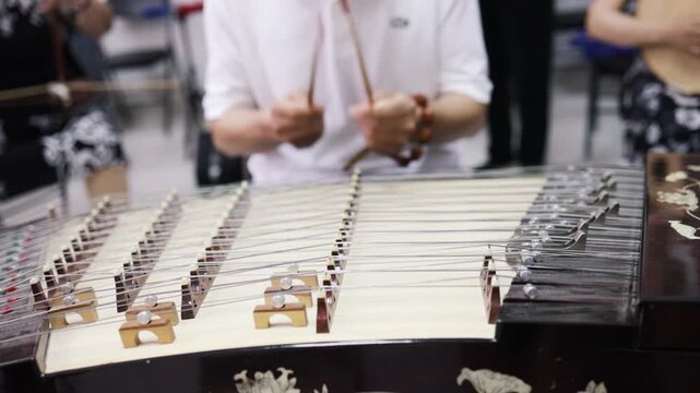 Chinese musician plays Dulcimer - old wooden musical instrument. Close up.