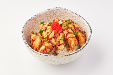 Bowl of crispy fried chicken served over steamed rice, garnished with green onions, red fish roe, and drizzled with savory sauce, creating flavorful and appetizing dish