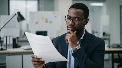 Focused black businessman reviewing financial documents in a modern office environment - Powered by Adobe