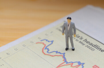 Fototapeta premium Miniature Businessman Standing on Financial Graph Symbolizing Market Influence