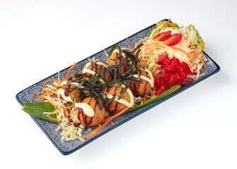 Crispy takoyaki balls garnished with seaweed, mayonnaise, and sauce, served on decorative plate with fresh shredded vegetables, pickled ginger, and creamy salad