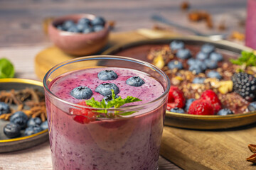 Summer scene: cold blueberry and mango smoothie on a terrace, with blueberries scattered on the table in the sun