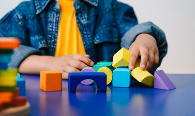 Child playing with colorful wooden blocks on blue table - Toddler, School learning and development concept