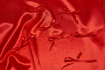 Beautiful red satin fabric with small bows arranged artistically for a creative project or celebration