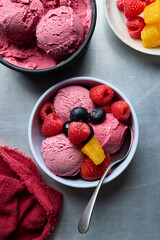 Top view Ice cream yogurt fruit salad in a bowl with spoon on light blue background