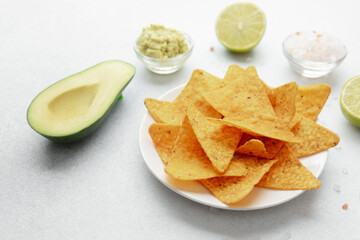 Nachos with avocado, guacamole, lime and salt on white table