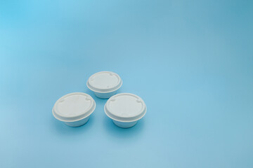 Three small white biodegradable food containers with lids, arranged on a blue background. Perfect for sustainability, zero waste, plastic free, compostable