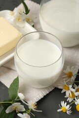 Fresh dairy products and flowers on grey wooden table, closeup