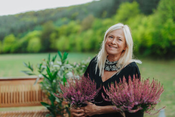 Mature woman standing by potted heathers on terrace.