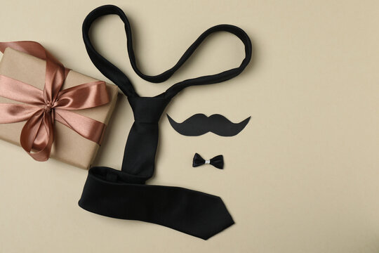 Father's Day. composition with gift box, glasses, cup of coffee and tie on beige background.
