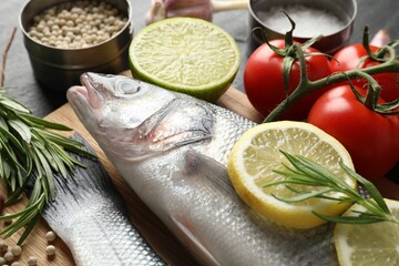 Fresh raw seabass with spices on black table, closeup. Fish and seafood delicacies