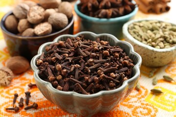 Different aromatic spices on orange tablecloth, closeup