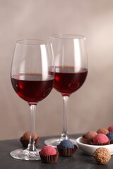 Delicious truffle bonbons and wine on black table against grey background