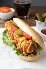 Tasty hot dog with vegetables, mustard and ketchup on table, closeup