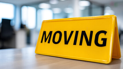 Yellow 'Moving' sign on a desk in an office environment