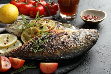 Tasty roasted dorado fish served on black table, closeup. Homemade seafood dish