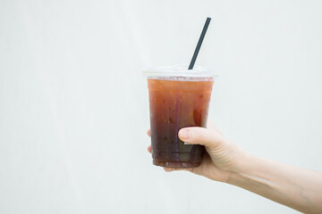 Hand holding a glass of cold coffee on a white background