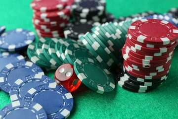 Casino chips and die on green table, closeup