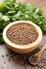 Fresh cilantro and coriander seeds on wooden table, closeup
