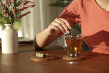 Woman hand stirring tea at sunset at home