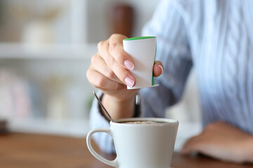 Woman hand throwing saccharin on coffee