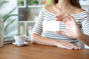 Woman hand showing blank credit card on a table at home