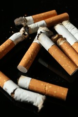 Cigarette butts with ash on black background, closeup