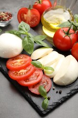 Tasty mozzarella cheese, tomatoes, basil and spices on grey table, closeup