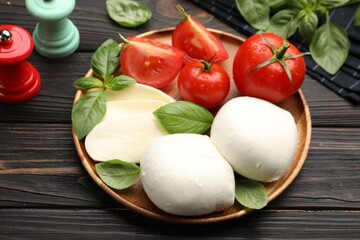 Tasty mozzarella cheese, tomatoes, basil and spices on wooden table, closeup
