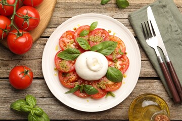 Tasty salad Caprese served with pesto sauce on wooden table, flat lay