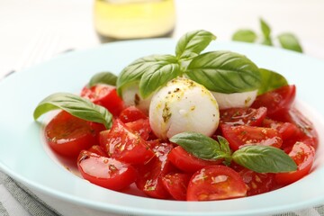 Tasty salad Caprese with mozzarella, tomatoes, basil and spices on table, closeup