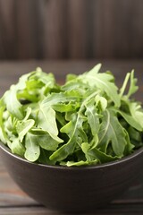 Fresh ripe green arugula leaves on dark wooden table, closeup
