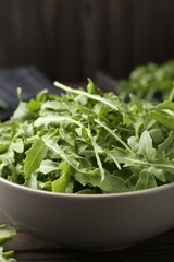 Fresh ripe green arugula leaves on dark wooden table, closeup