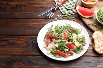 Tasty salad with arugula and prosciutto served on wooden table, closeup. Space for text