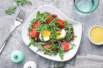 Tasty salad with arugula, vegetables and egg served on grey table, flat lay