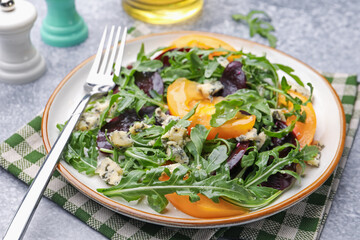 Tasty salad with arugula, blue cheese and vegetables on grey textured table, closeup